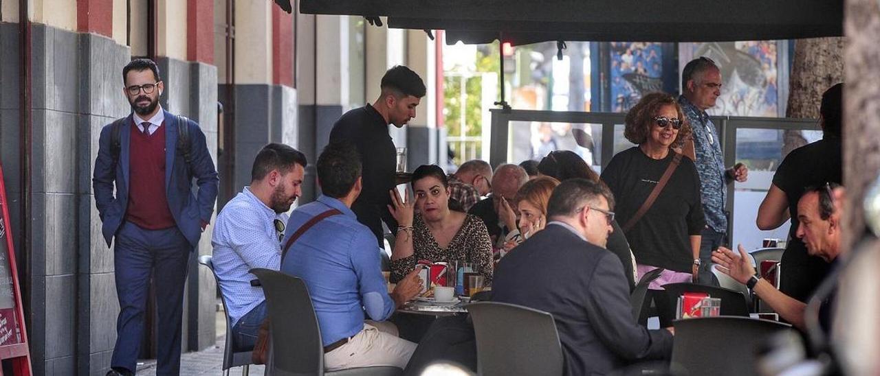 Un camarero sirve una mesa en una terraza repleta de gente en Santa Cruz de Tenerife.