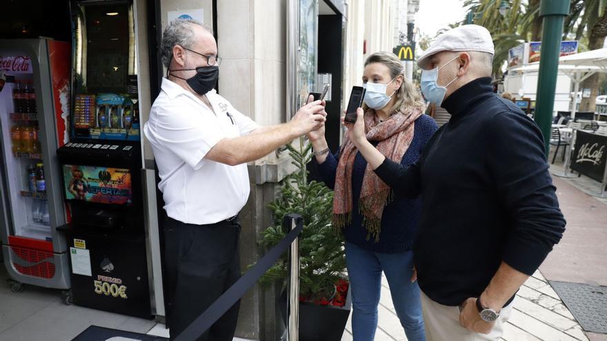 Unos  clientes muestran el pasaporte Covid para acceder a un bar del centro de Málaga. | ÁLEX ZEA