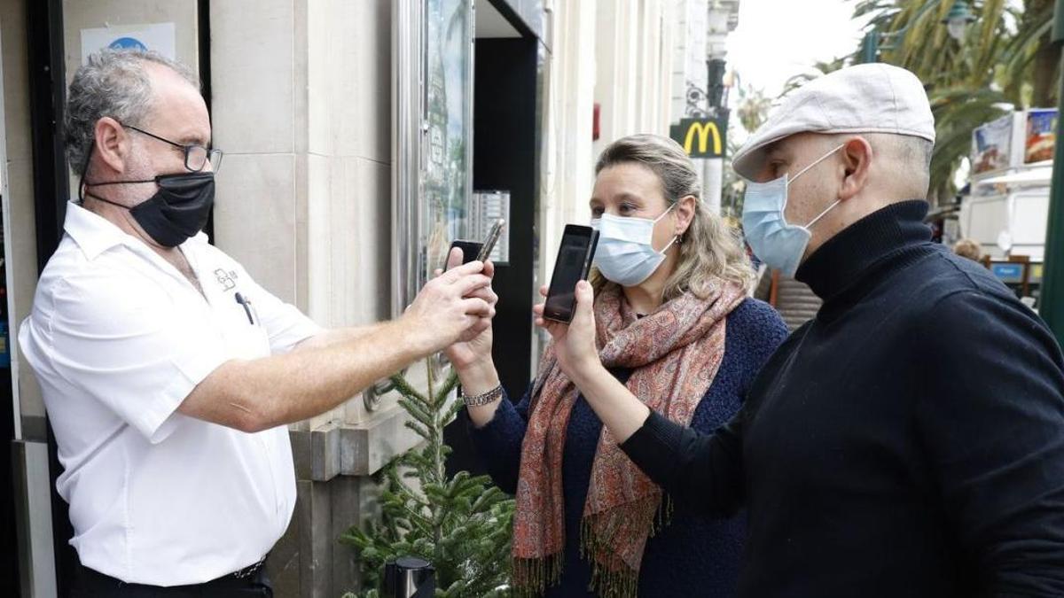 Unos clientes muestran el pasaporte Covid para acceder a un bar del centro de Málaga.