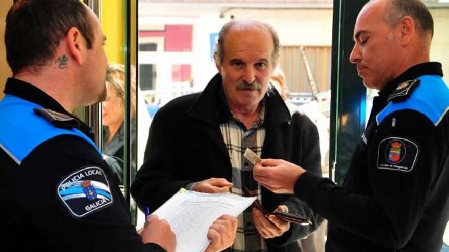 Dos agentes de la Policía Local identifican a uno de los asistentes al pleno del pasado lunes.  // Iñaki Abella