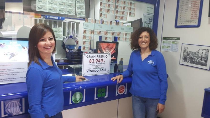 Dos trabajadoras de la administración posan junto al cartel del premio.