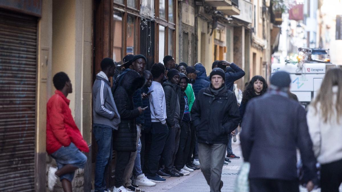 Un grupo de migrantes frente al hotel en el que se alojan en Zaragoza.