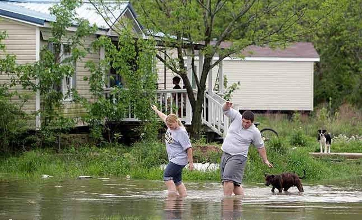 Dues persones caminen sobre terrenys inundats per tornar a casa seva, a Missouri (EUA), on les desbordades aigües del Riu Negre han produït nombroses inundacions.