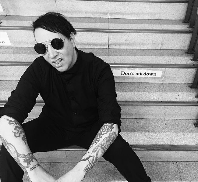 Marilyn Manson sentado en unas escaleras
