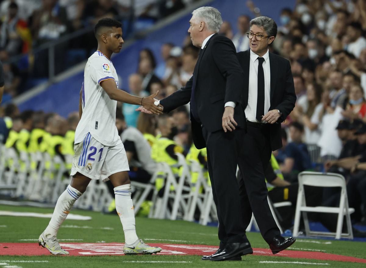 MADRID, 12/05/2022.- El delantero del Real Madrid Rodrygo de Goes (i) saluda al entrenador Carlo Ancelotti (c) al ser sustituido, durante el partido de Liga en Primera División ante el Levante que disputan hoy jueves en el estadio Santiago Bernabéu, en Madrid. EFE/Juanjo Martín