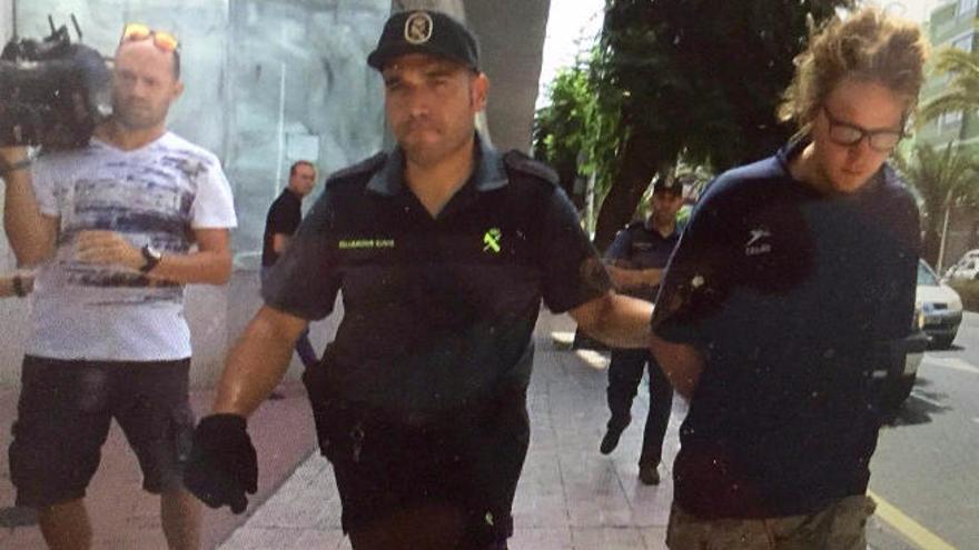 El joven detenido como presunto autor del incendio, conducido por un guardia civil, ayer.