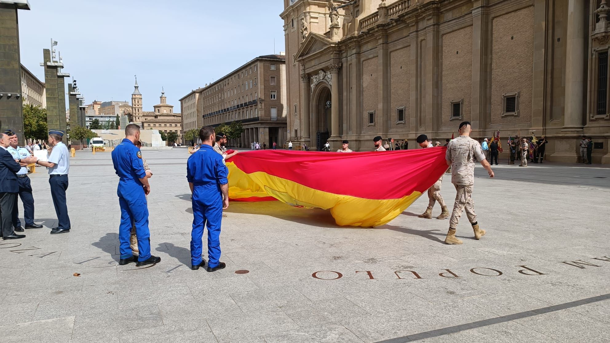 Preparativos para el despliegue aéreo de una bandera de España en la Plaza del Pilar