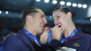 Gold medalists Dennis Gonzalez Boneu, right and Iris Tio Casas of Spain bites on their medals for photos after the mixed duet free final of artistic swimming at the World Aquatics Championships, in Singapore, Friday, July 25, 2025. (AP Photo/Ng Han Guan)