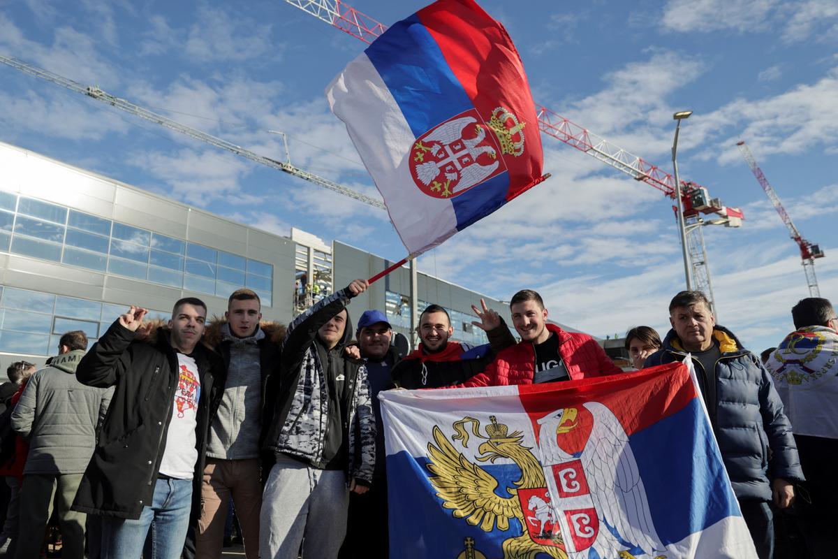 Fans del tenista Novak Djokovic agitan una bandera de Serbia, mientras le esperan en el Aeropuerto Nikola Tesla de Belgrado.