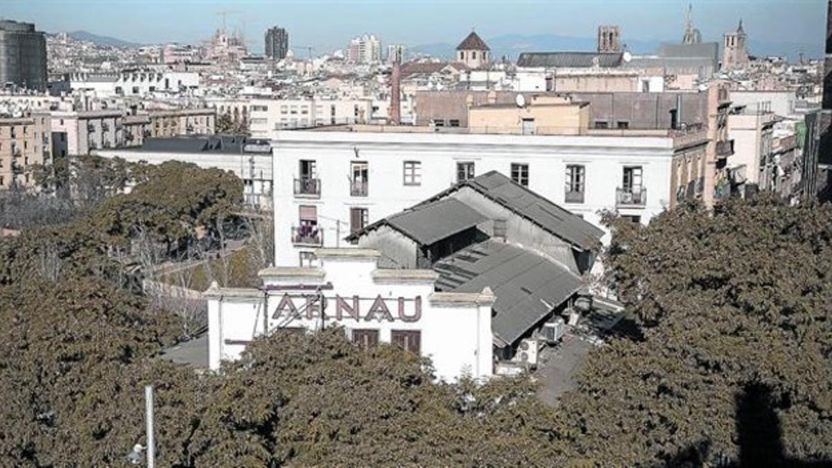 El teatro Arnau tras una frondosa arboleda, en la esquina del Paral·lel y Nou de la Rambla, edificio abandonado y apuntalado, adquirido por el ayuntamiento en marzo del año 2011.