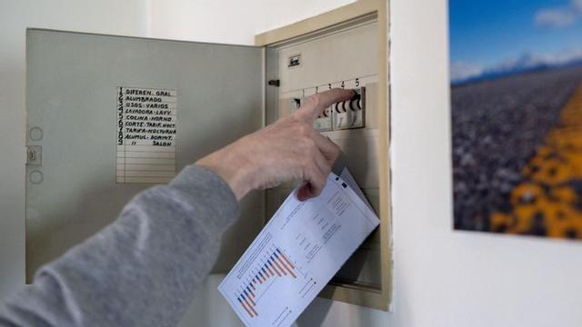 Un hombre sube los plomos de la luz con una factura de luz en la mano. | // ALBERTO ORTEGA / E. P.