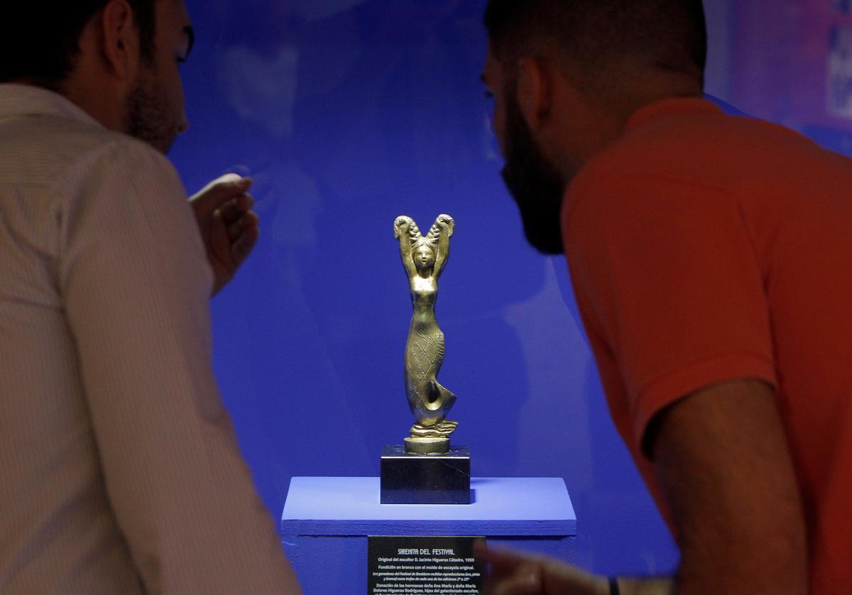 Dos personas contemplan la primera estatuilla de la Sirenita que se entregó en el Festival de la Canción de Benidorm.