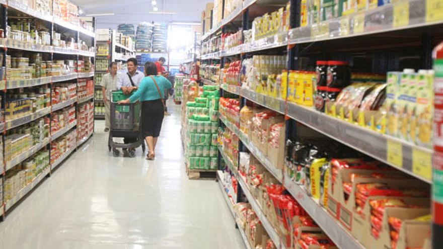 Varias personas hacen la compra en un supermercado.