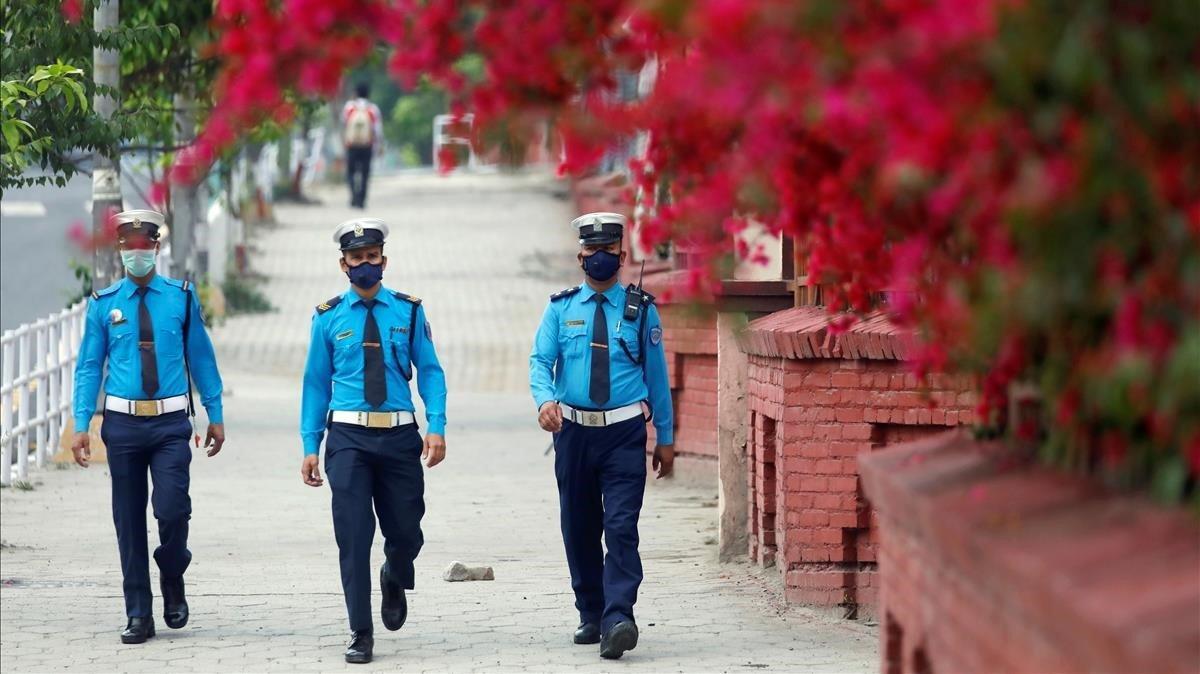 Tres policías de tráfico caminan por una calle desierta en Kathmandú, Nepal.