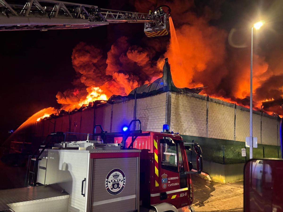 Las llamas salen por la cubierta de la nave industrial.