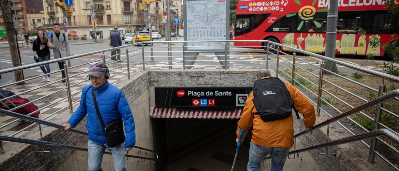 Gustavo -a la derecha- baja al metro con una muleta en Plaça de Sants, una de las paradas del metro de Barcelona sin ascensores.