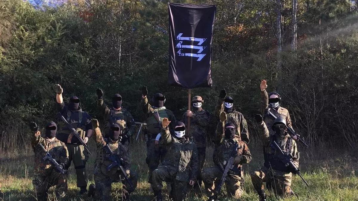 Imagen propagandística de The Base, con su bandera y miembros haciendo el saludo nazi.