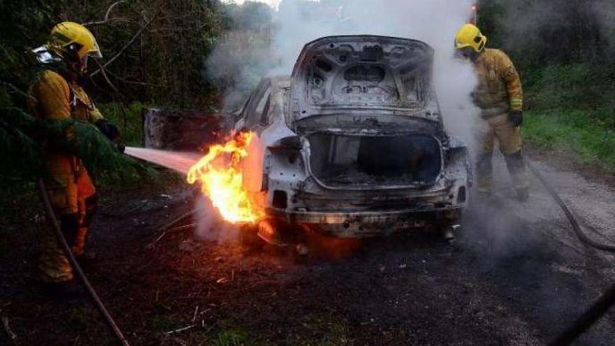 Los bomberos apagan las llamas del coche donde obligaron a las víctimas a introducirse. // N.P.