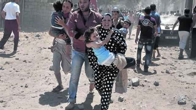Una mujer palestina carga con una niña, ayer en Gaza, tras un ataque aéreo israelí.