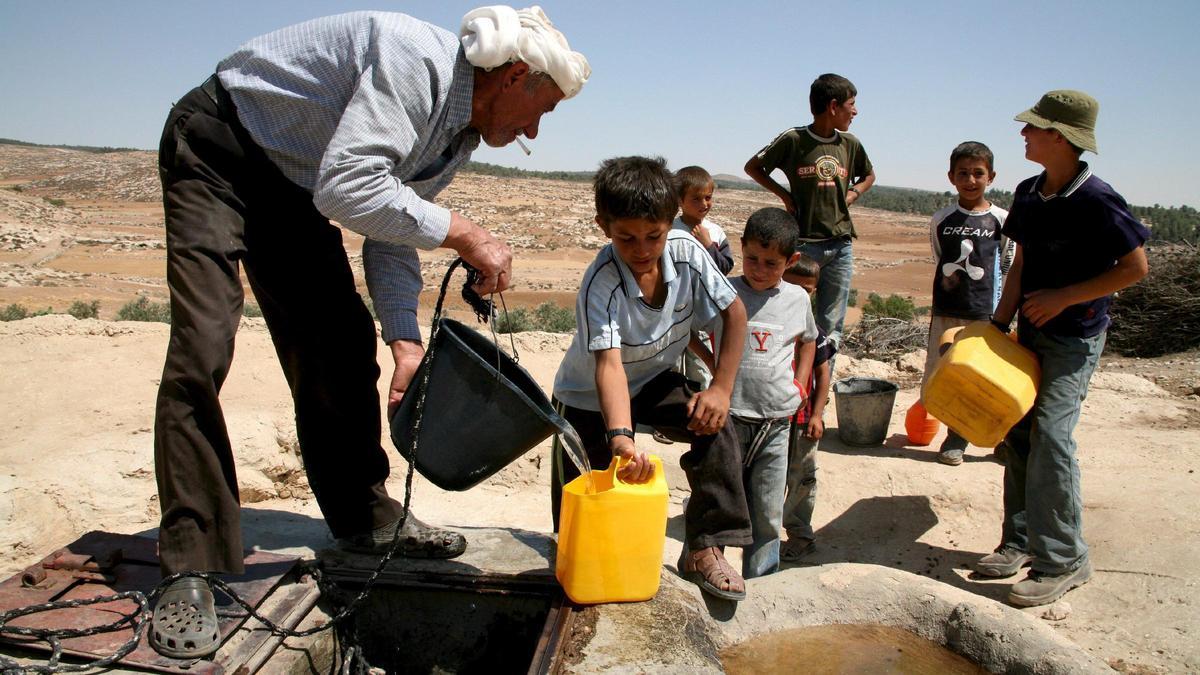 Un xiquet palestí plena un bidó d’aigua en un pou a la ciutat cisjordana de Yatta.