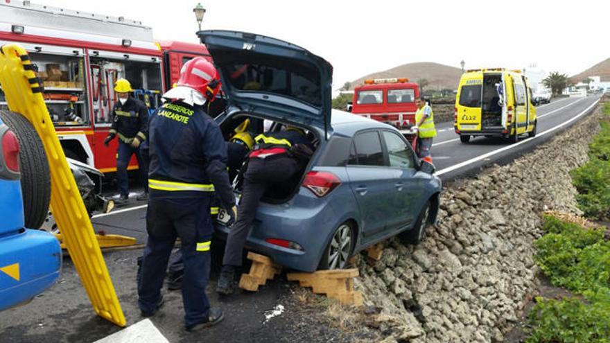 Los bomberos y otros efectivos, junto al coche accidentado en Tinajo.