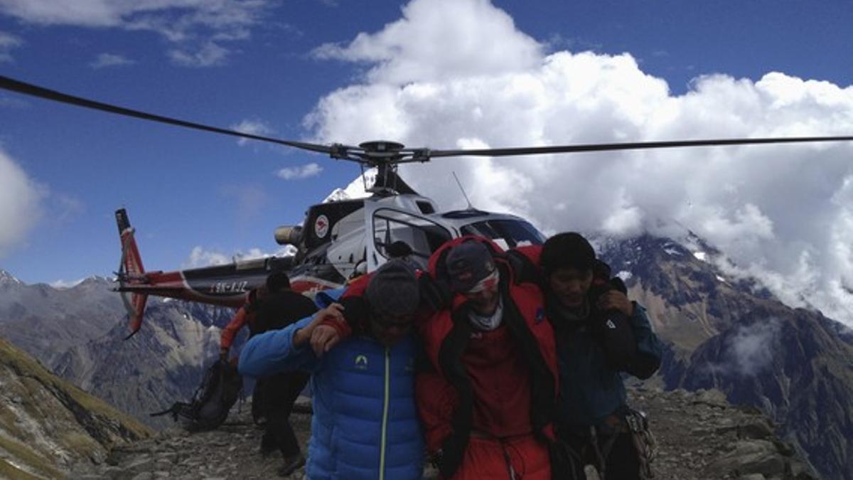 Miembros de los equipos de rescate evacuan a un afectado por el alud.