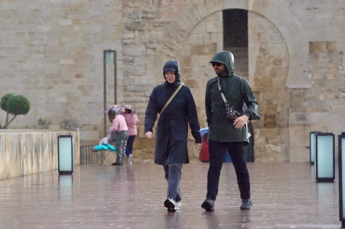 Viandantes bajo la lluvia en el Puente Romano de Córdoba.