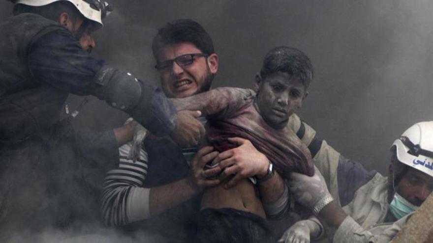 Un hombre rescata a un niño tras una explosión en Aleppo.