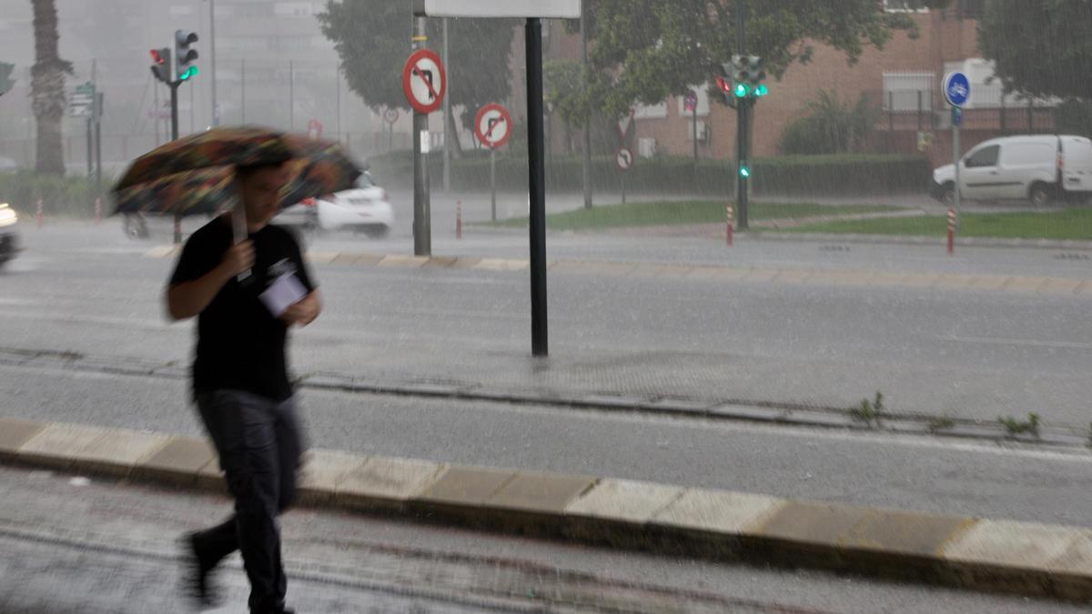 Un hombre corre bajo la fuerte lluvia en Murcia.