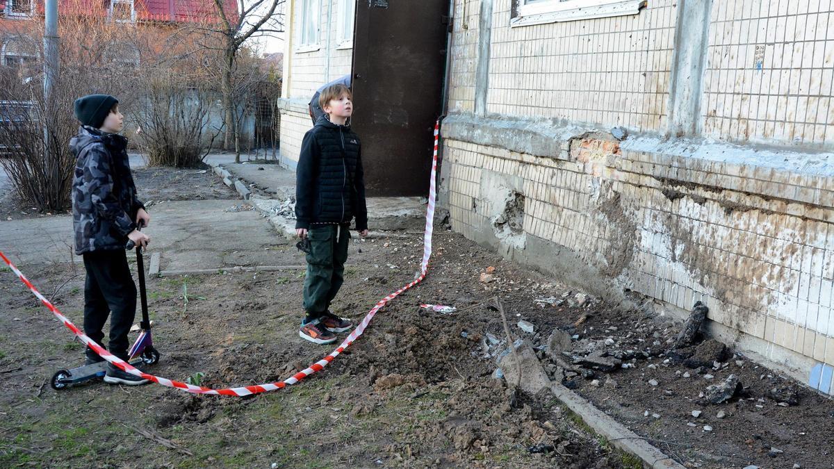 Un parell de nens inspeccionen una zona afectada per un atac rus a Kíiv
