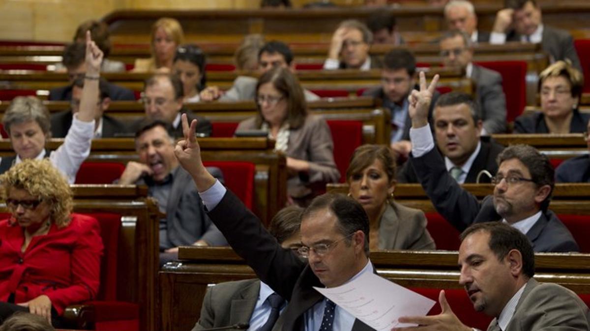 Los portavoces Jordi Turull (CiU) --en primer término--, Enric Millo (PPC) y Anna Simó (ERC) indican a sus grupos qué votar, este viernes en el Parlament.