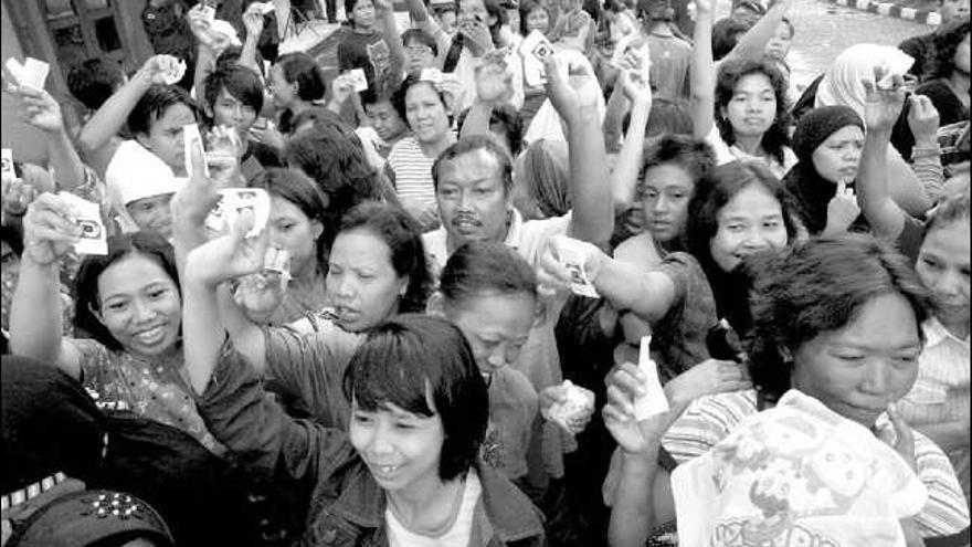 Un grupo de personas aguarda para conseguir una de las raciones de arroz gratis que da un partido político indonesio en Yakarta.