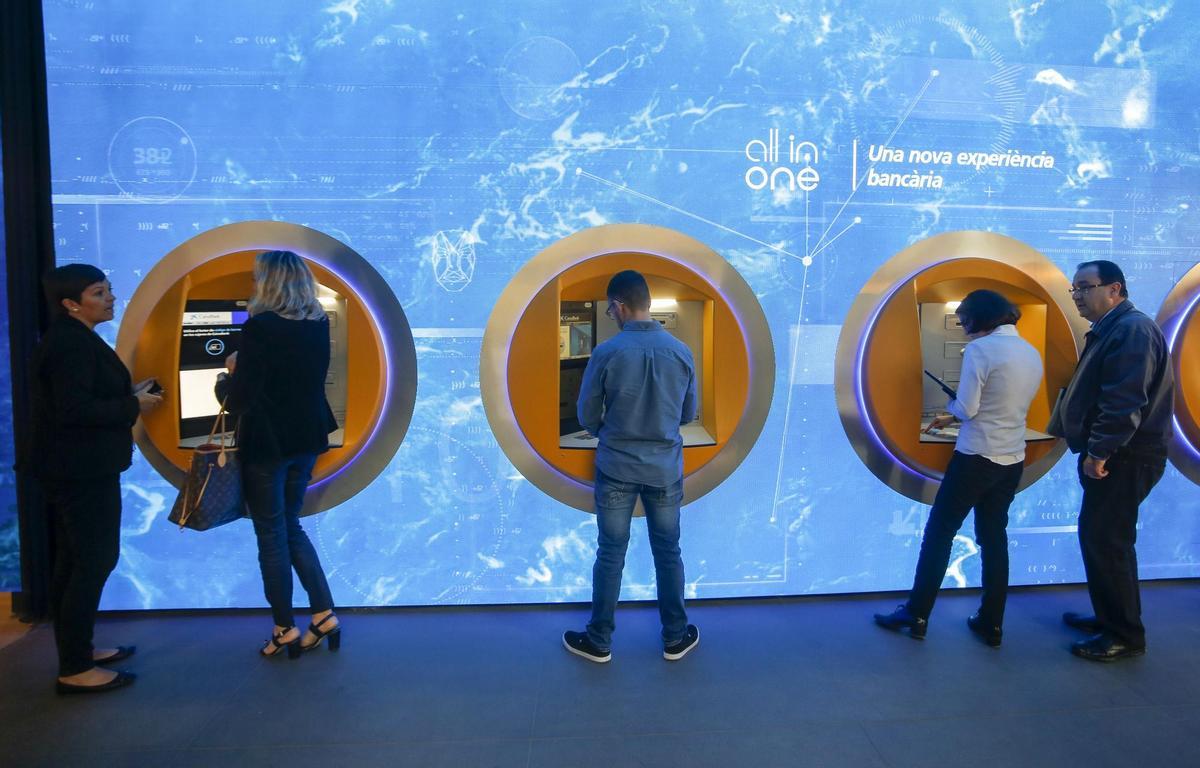 Clientes sacan dinero del cajero de un banco en una imagen de archivo