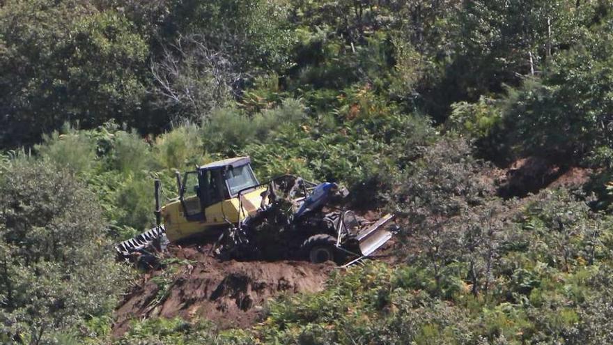 Un bulldozer (a la izquierda ) trata de levantar los restos del tractor para rescatar a la víctima. // Jesús Regal