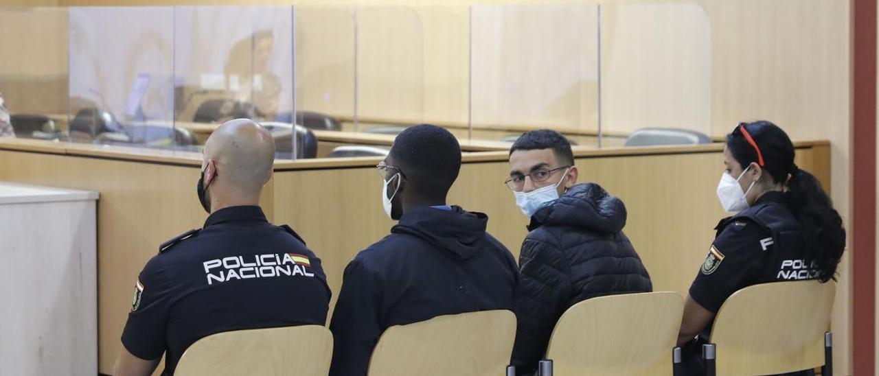 En primer término, el joven que denunció su secuestro, con los dos acusados, en el banquillo, custodiados por la Policía Nacional, ayer, en la sección octava de la Audiencia. | M. L.