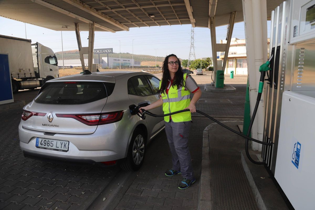 Una trabajadora llena el tanque de gasolina de un vehículo en la gasolinera.