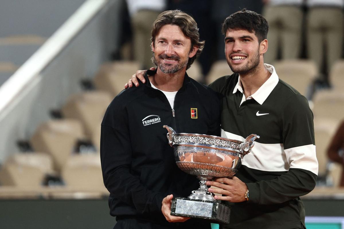 (FILES) Spain's Carlos Alcaraz poses with his Spanish coach Juan Carlos Ferrero (L) after winning against Italy's Jannik Sinner at the end of their men's singles final match on day 15 of the French Open tennis tournament on Court Philippe-Chatrier at the Roland-Garros Complex in Paris on June 8, 2025. Men's tennis world number one Carlos Alcaraz announced on December 17, 2025 on social media he is splitting from his coach Juan Carlos Ferrero after seven hugely successful years. (Photo by Thibaud MORITZ / AFP)