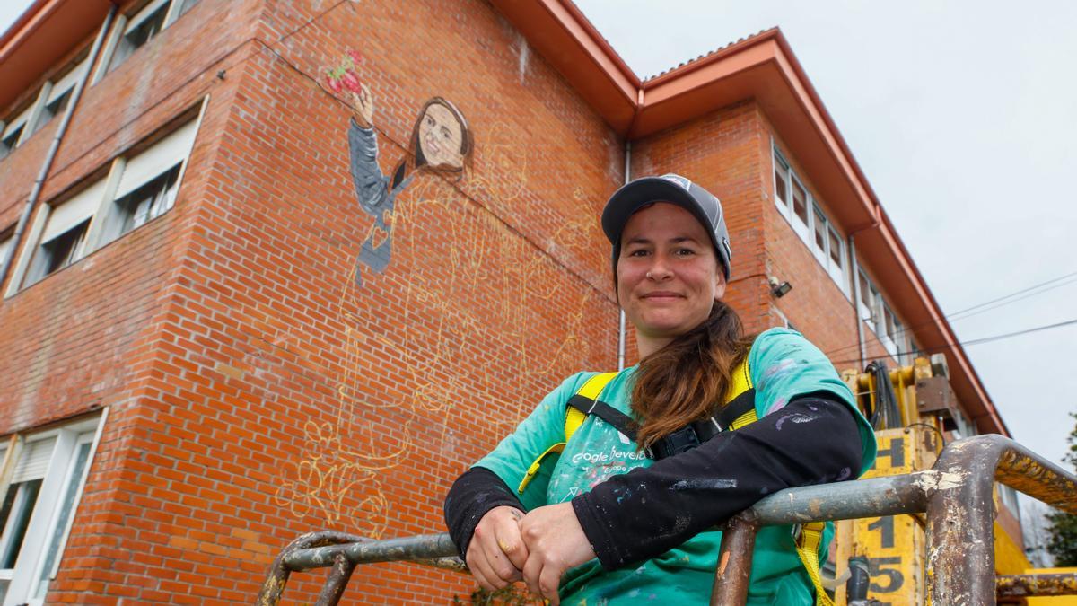 La artista Eva Casais posa junto al mural durante su pintura