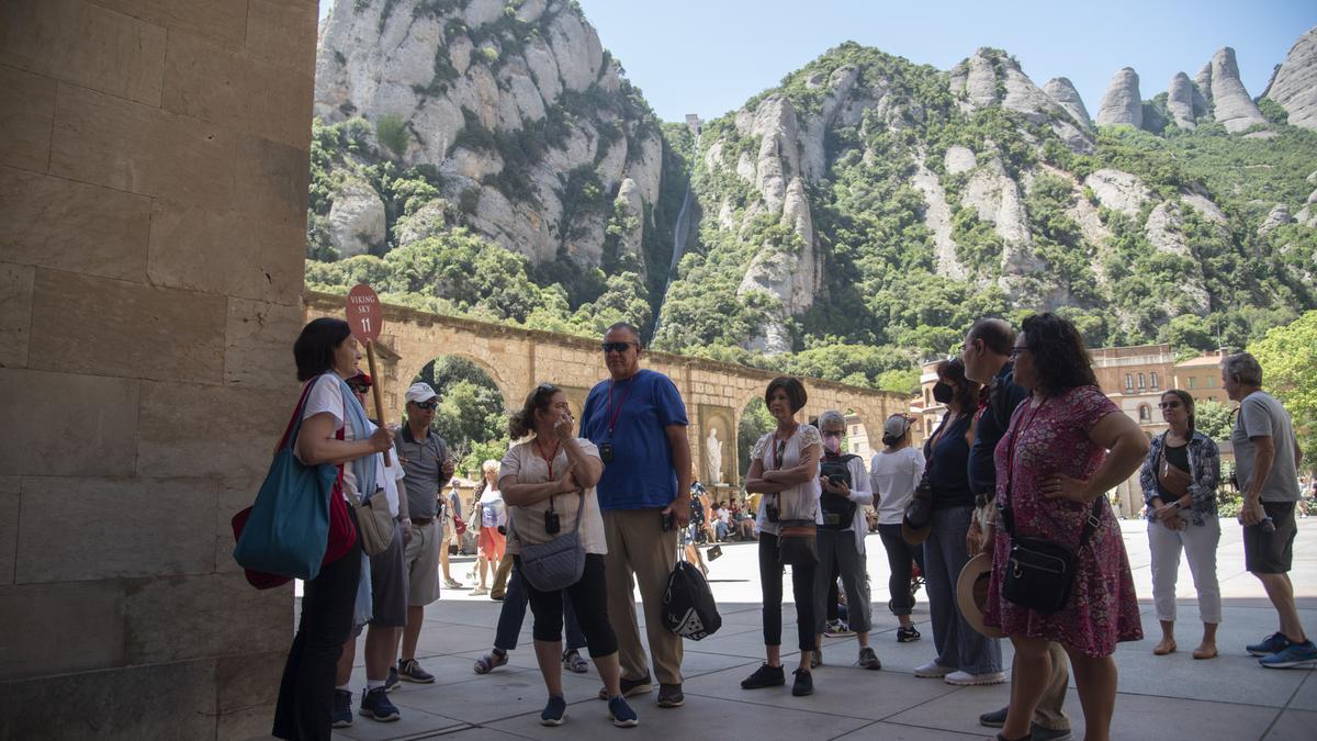 Un grup de turistes a Montserrat seguint les indicacions d'una guia, l'estiu passat