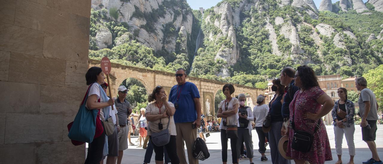 Un grup de turistes a Montserrat seguint les indicacions d'una guia, l'estiu passat
