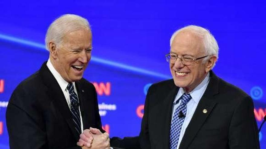 Biden y Sanders se estrechan sonrientes la mano tras el debate. // EP