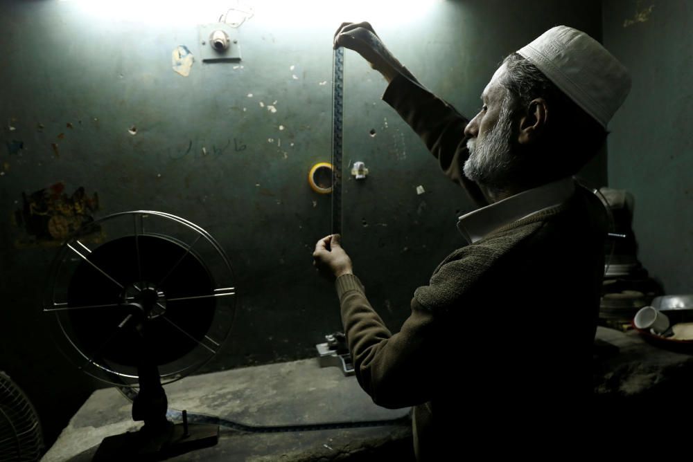 A worker checks a film strip at a cinema house ...