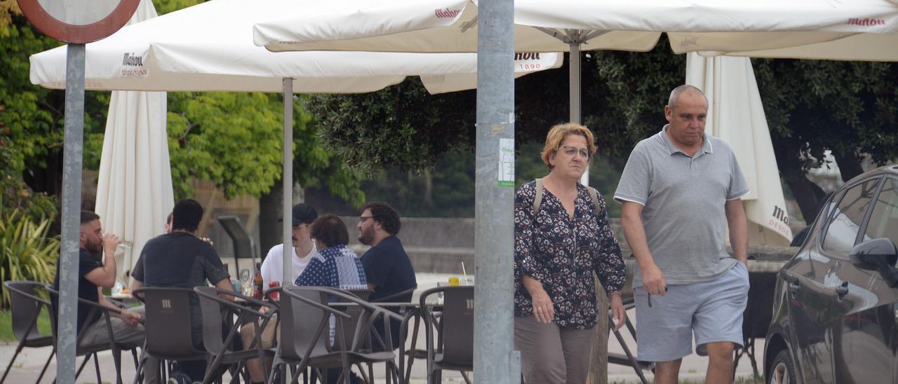 Vecinos paseando por delante de una terraza, ayer, en Banda do Río