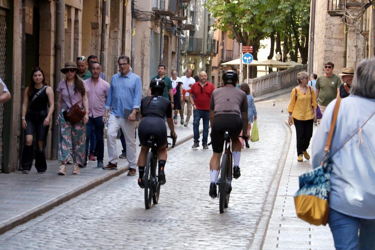 Dos ciclistes passant pel carrer Ballesteries de Girona.