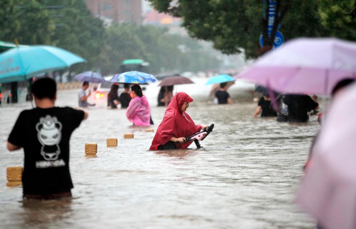 Gente caminando por una carretera inundada de Zhengzhou, en la provincia china de Henan, en 2021.