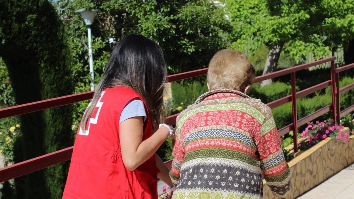 Una voluntaria de Cruz Roja acompaña a una persona mayor.