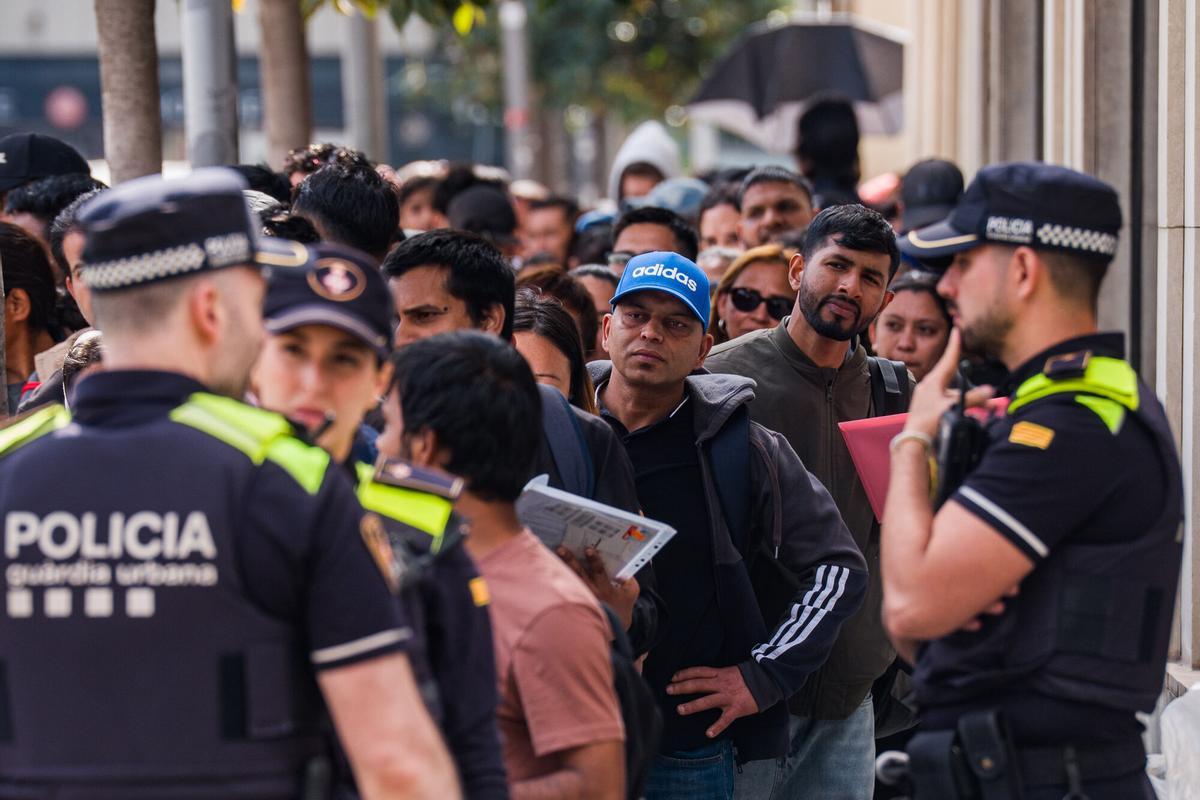 Caos y una larga cola de personas que esperan regularizar su situación en España en la Oficina de Benestar Social i Família de Barcelona-Sants/Eixample.