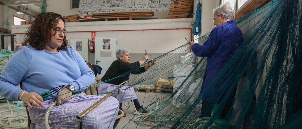 Tres de las seis redeiras de la Asociación Atalaia de A Guarda, en la nave donde trabajan, ayer por la mañana.   | // ANXO GUTIÉRREZ