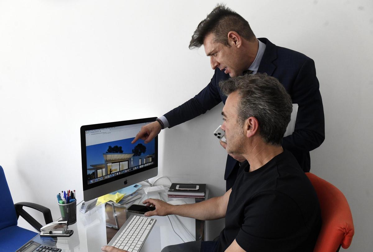 José Castellanos, de pie, señala una casa en la pantalla del ordenador junto a su socio, Javier Marín, en la inmobiliaria Mondial de Murcia.
