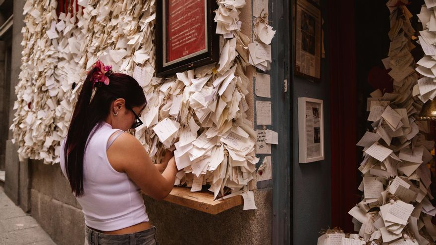 Una chica coloca su deseos en la fachada de Peque Story, en el centro de Madrid.